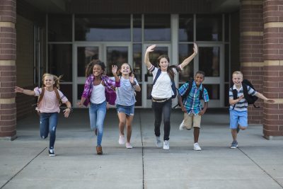 一群学校学生在离开学校大楼时跑步和社交，练习新冠肺炎后的社交技能