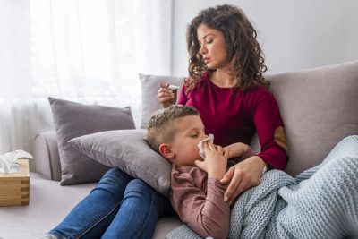 年轻的母亲抱着她生病的儿子，与冬天的病毒作斗争，一起躺在沙发上