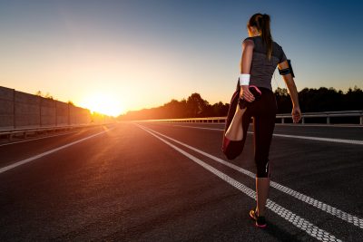越野长跑运动员在夕阳下伸展身体