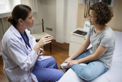Doctor consults with a teen girl during her first gynecologist visit